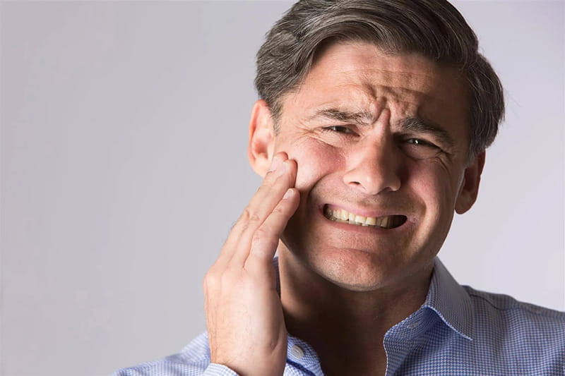 Image of a man holding his jaw, indicating jaw pain.